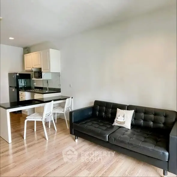 Modern open-layout kitchen and living room with sleek black sofa and dining area.