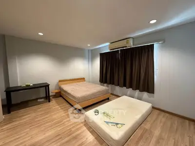 Spacious bedroom with wooden flooring and air conditioning, ideal for comfort and relaxation.
