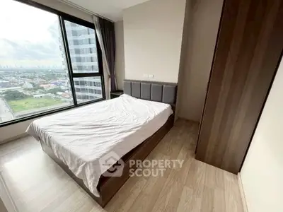 Modern bedroom with large window offering stunning city view in high-rise apartment.