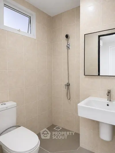 Modern bathroom with sleek fixtures and neutral tiles, featuring a shower and a window for natural light.