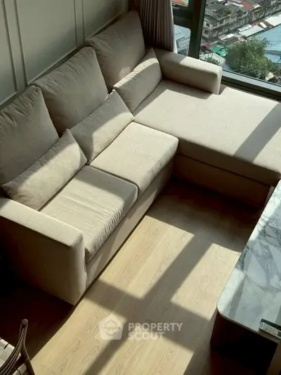 Cozy living room with beige sectional sofa and large window view