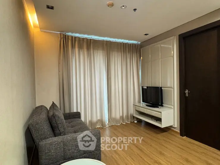 Cozy living room with modern sofa and TV, featuring elegant wooden flooring and soft lighting.