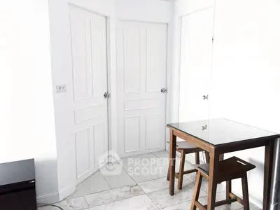 Minimalist dining area with glass table and wooden chairs in a bright white room