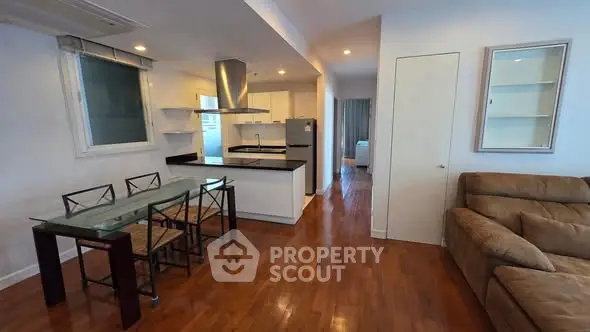 Spacious open-plan living room with modern kitchen and dining area, featuring hardwood floors and contemporary furnishings.