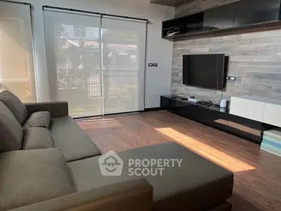 Modern living room with sleek design, large sofa, and wall-mounted TV, featuring natural light and stylish decor.