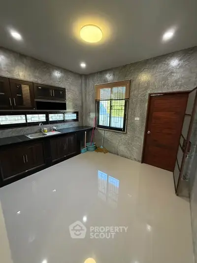 Spacious modern kitchen with sleek cabinets and large window, perfect for culinary enthusiasts.