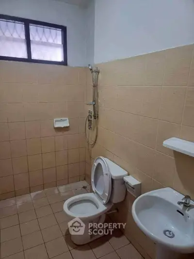 Simple bathroom with shower, toilet, and sink in a tiled setting.