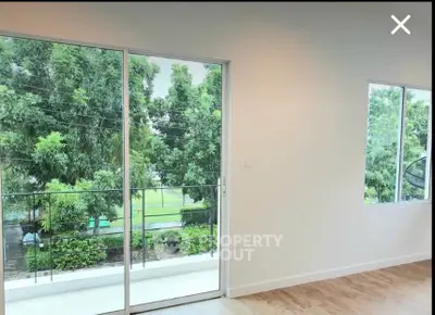 Bright room with large windows and balcony overlooking lush greenery.