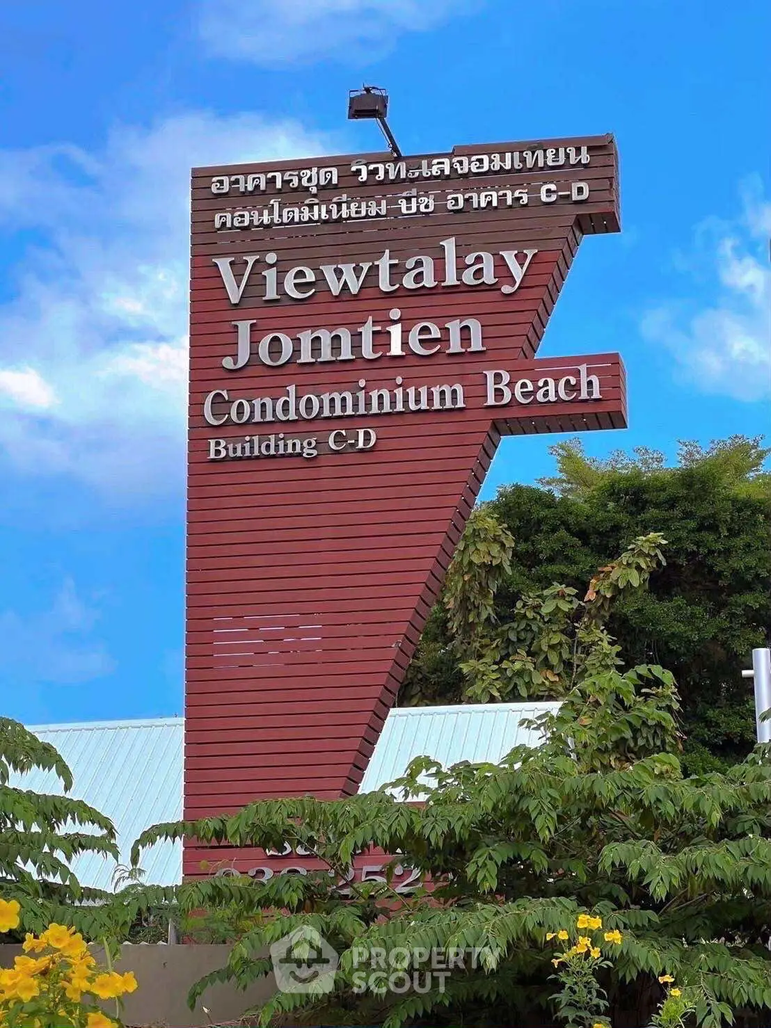 Viewtalay Jomtien Condominium Beach sign with lush greenery and clear blue sky.