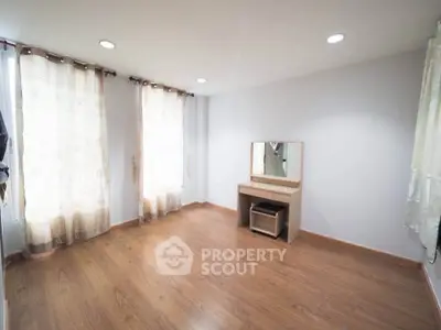 Spacious empty bedroom with wooden flooring and natural light