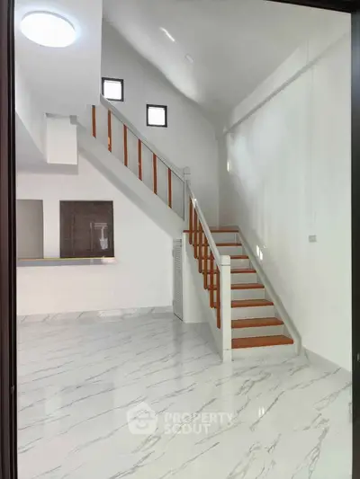 Modern interior with elegant staircase and marble flooring, showcasing open space and natural light.