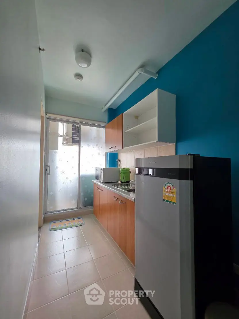 Compact kitchen with modern appliances and vibrant blue accent wall.