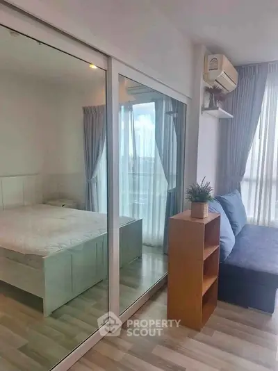 Modern bedroom with mirrored closet and cozy seating area in a bright apartment.