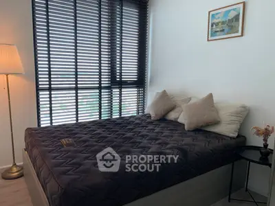 Cozy bedroom with large window and modern decor, perfect for relaxation.