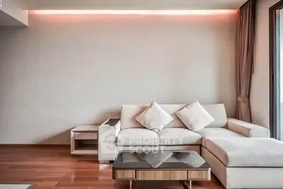 Modern living room with stylish sofa and wooden flooring, featuring elegant lighting and a cozy ambiance.