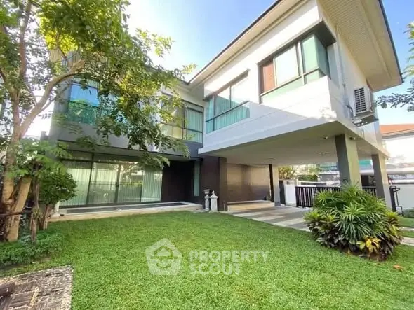 Modern two-story house with lush green lawn and large windows, perfect for family living.