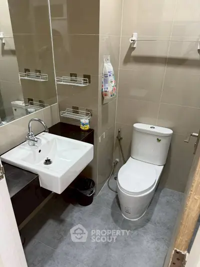 Modern bathroom with sleek fixtures and neutral tiles, featuring a compact design for efficient space use.