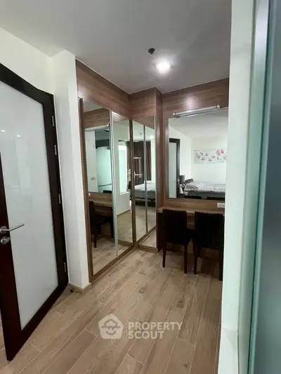 Modern bedroom with mirrored wardrobe and wooden flooring