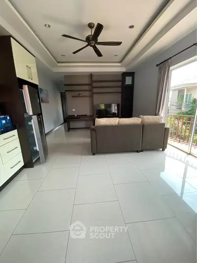 Spacious living room with modern ceiling fan and large windows for natural light.