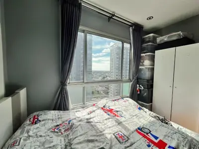 Cozy bedroom with large window offering stunning city view, featuring modern decor and ample natural light.