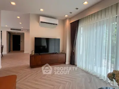 Spacious modern living room with large TV and elegant curtains