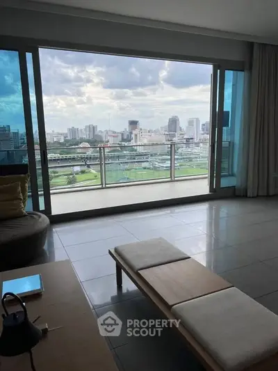 Spacious living room with stunning city view from large glass windows and balcony.