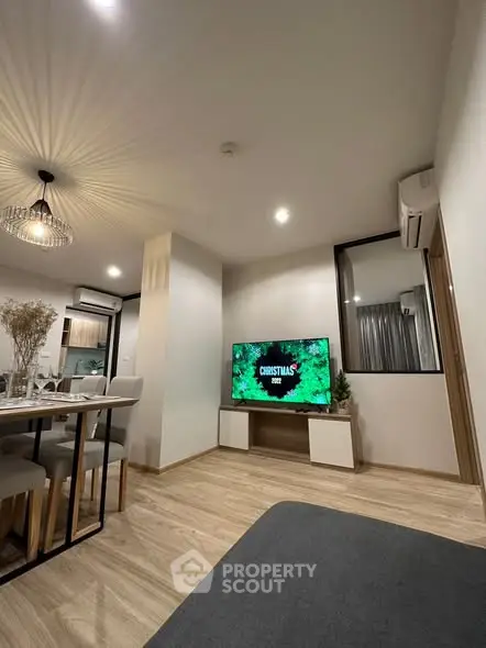 Modern living room with stylish decor and open layout, featuring a cozy dining area and large TV.