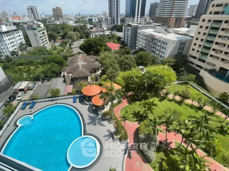 Stunning aerial view of luxury apartment complex with pool and lush gardens in vibrant cityscape.