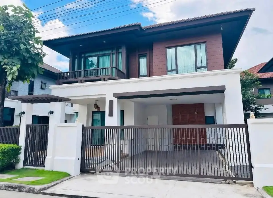 Modern two-story house with gated driveway and lush greenery, perfect for family living.