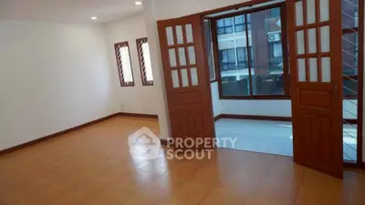Spacious living room with wooden flooring and large windows for natural light.