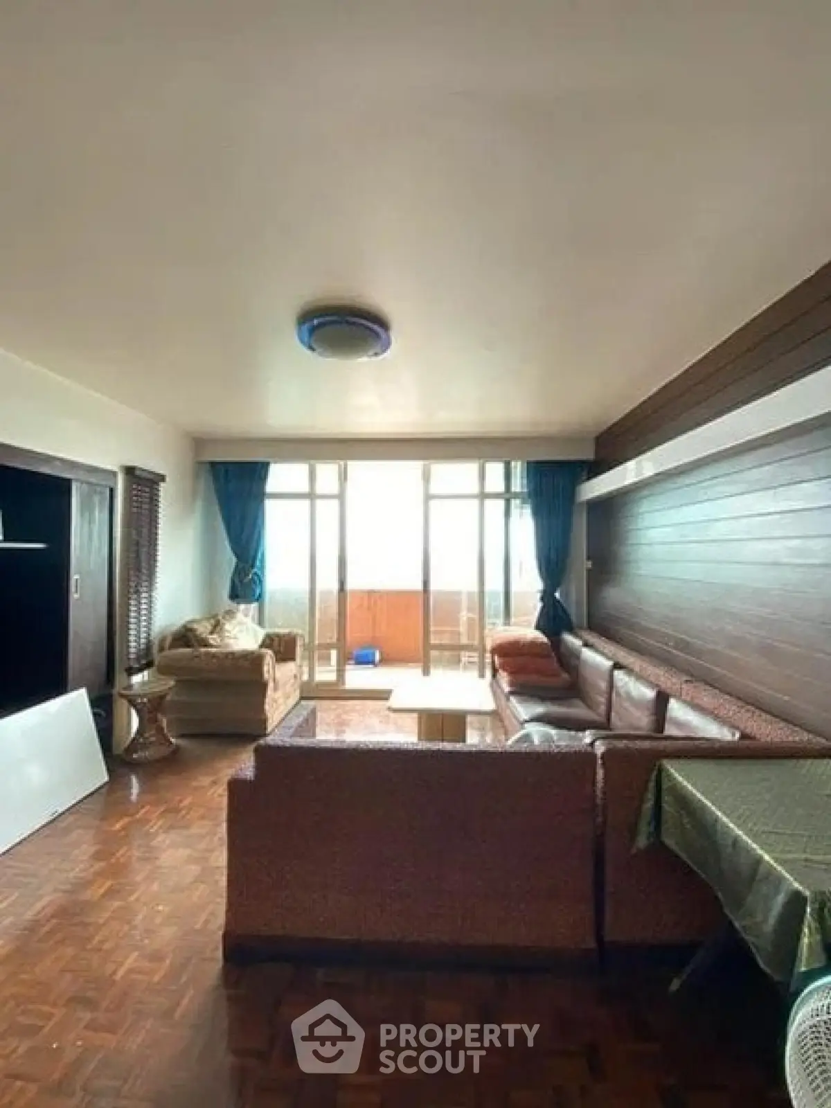 Spacious living room with large windows and cozy seating area in a modern apartment.