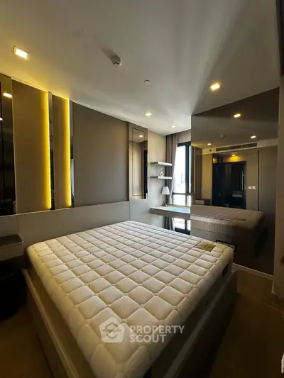Modern bedroom with stylish lighting and large mirror, featuring a comfortable bed and sleek design.