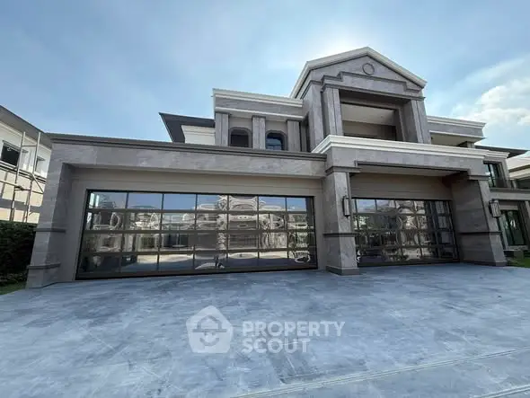 Luxurious modern mansion with expansive glass garage doors and elegant architecture.