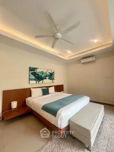 Spacious bedroom with modern decor and ceiling fan in a luxury apartment.