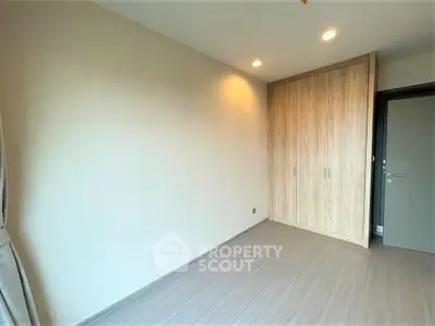 Spacious empty bedroom with built-in wooden wardrobe and modern lighting