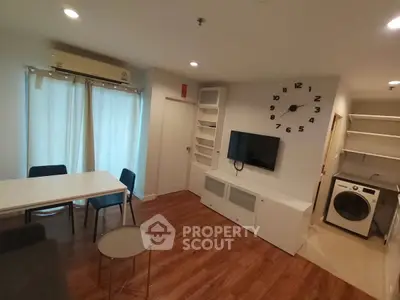 Modern living room with wooden flooring, wall-mounted TV, and washing machine in open layout.