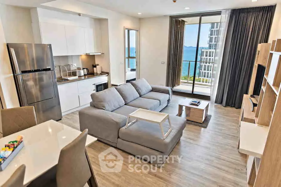 Modern open-plan living room with kitchen and balcony offering stunning sea view.