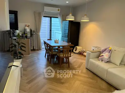 Modern living room with stylish dining area and cozy seating, featuring elegant lighting and wooden flooring.