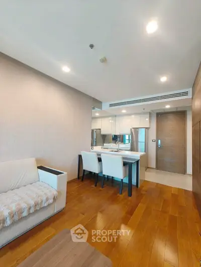 Modern living room with wooden flooring and elegant dining area in a stylish apartment.