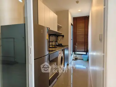 Modern kitchen with sleek appliances and washing machine in compact layout