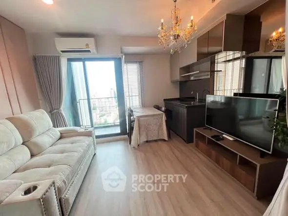 Modern living room with elegant chandelier and open kitchen layout in a stylish apartment.
