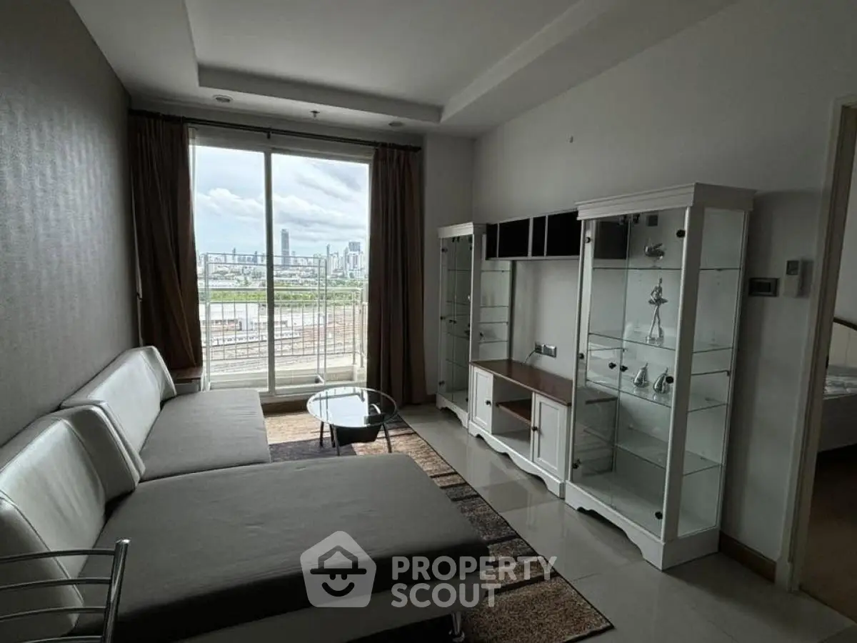 Spacious living room with modern furniture and city view balcony in high-rise apartment.