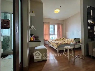 Cozy bedroom with wooden flooring and natural light, featuring a stylish bed and modern decor.