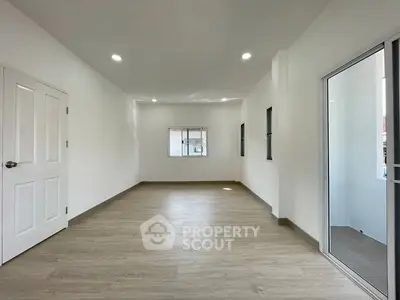 Spacious empty room with wooden flooring and bright natural light