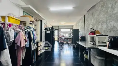 Spacious interior with modern kitchen and ample storage, featuring sleek black flooring and stylish concrete walls.