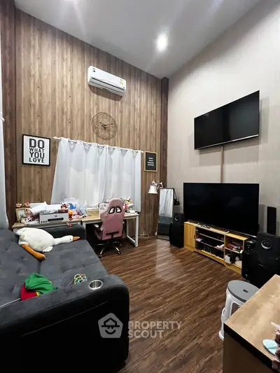 Stylish living room with modern decor, featuring dual TVs and cozy workspace.