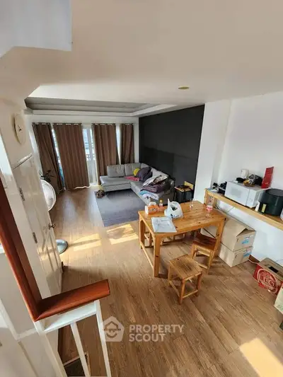 Spacious living room with wooden flooring and cozy furniture, perfect for family gatherings.