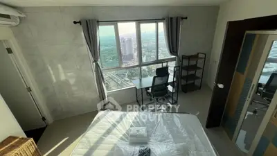 Modern bedroom with city view, featuring a desk and large window for natural light.