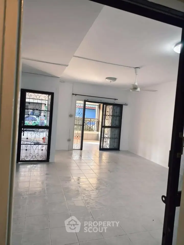 Spacious living room with large windows and tiled flooring, ideal for natural light and comfort.