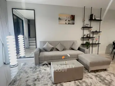 Modern living room with stylish gray sofa, chic decor, and elegant lighting.